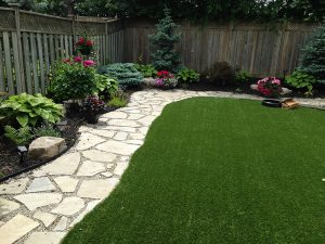 Dry Laid Flagstone path separating gardens and artificial grass