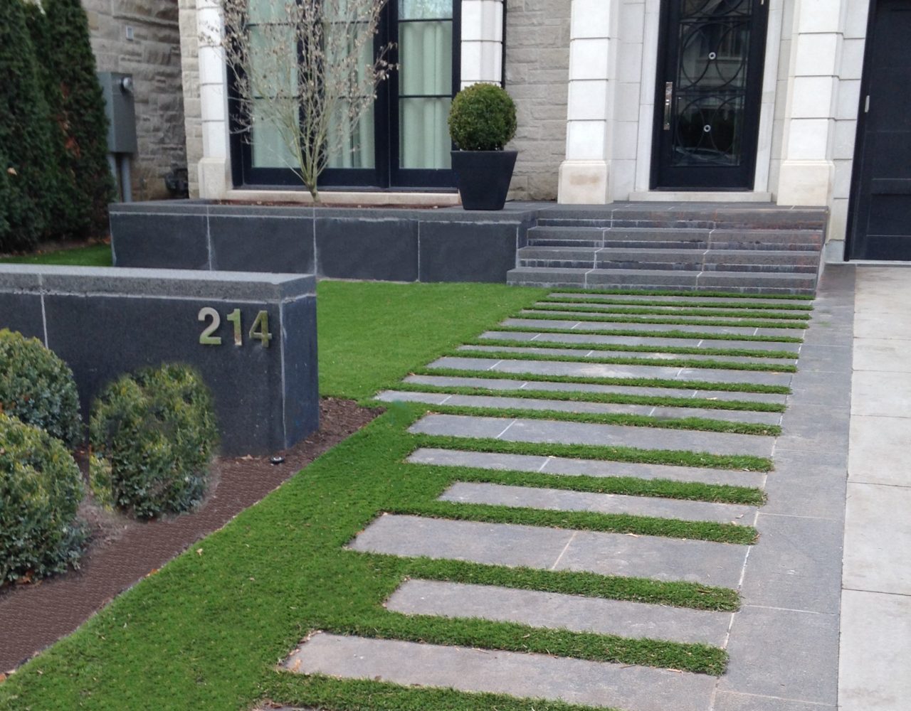 Nice walkway to front door with artificial grass between stone pavers