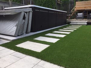 Above ground pool, flagstone path and artificial grass make for a lovely backyard