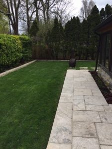 Hedging curbing patio accentuated by fake grass
